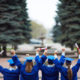 Backs of ecstatic students in graduation gowns holding diplomas