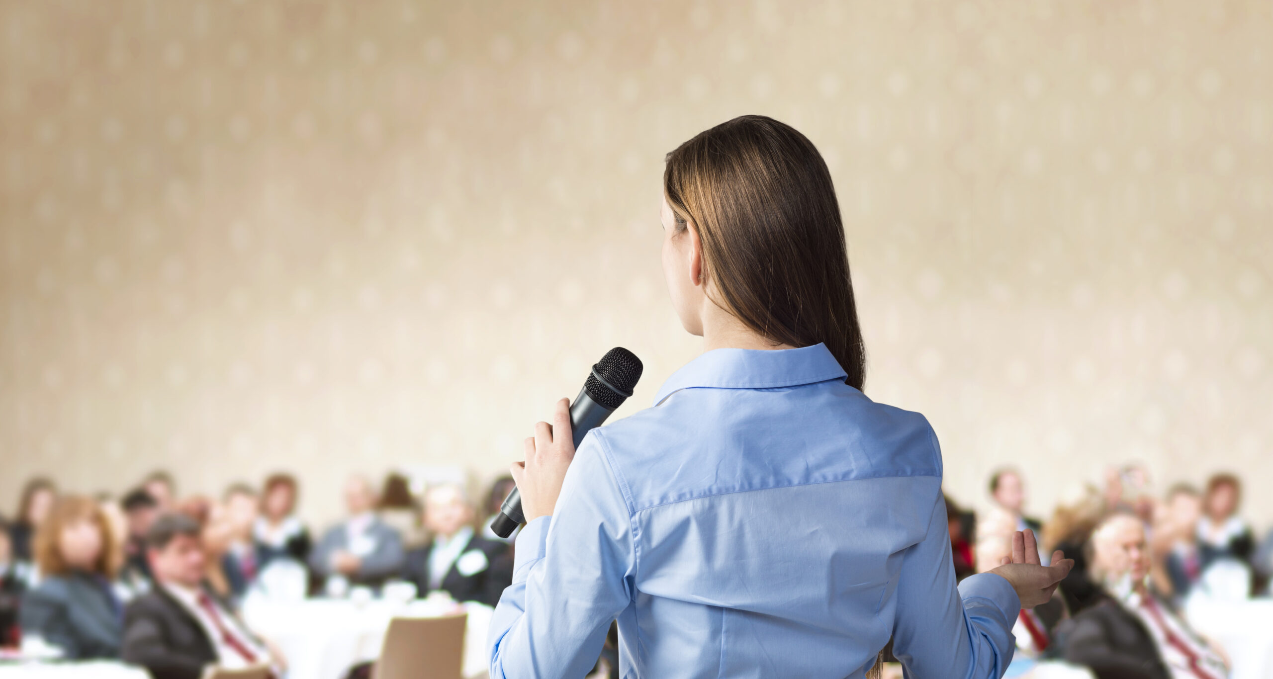 Beautiful business woman is speaking on conference.