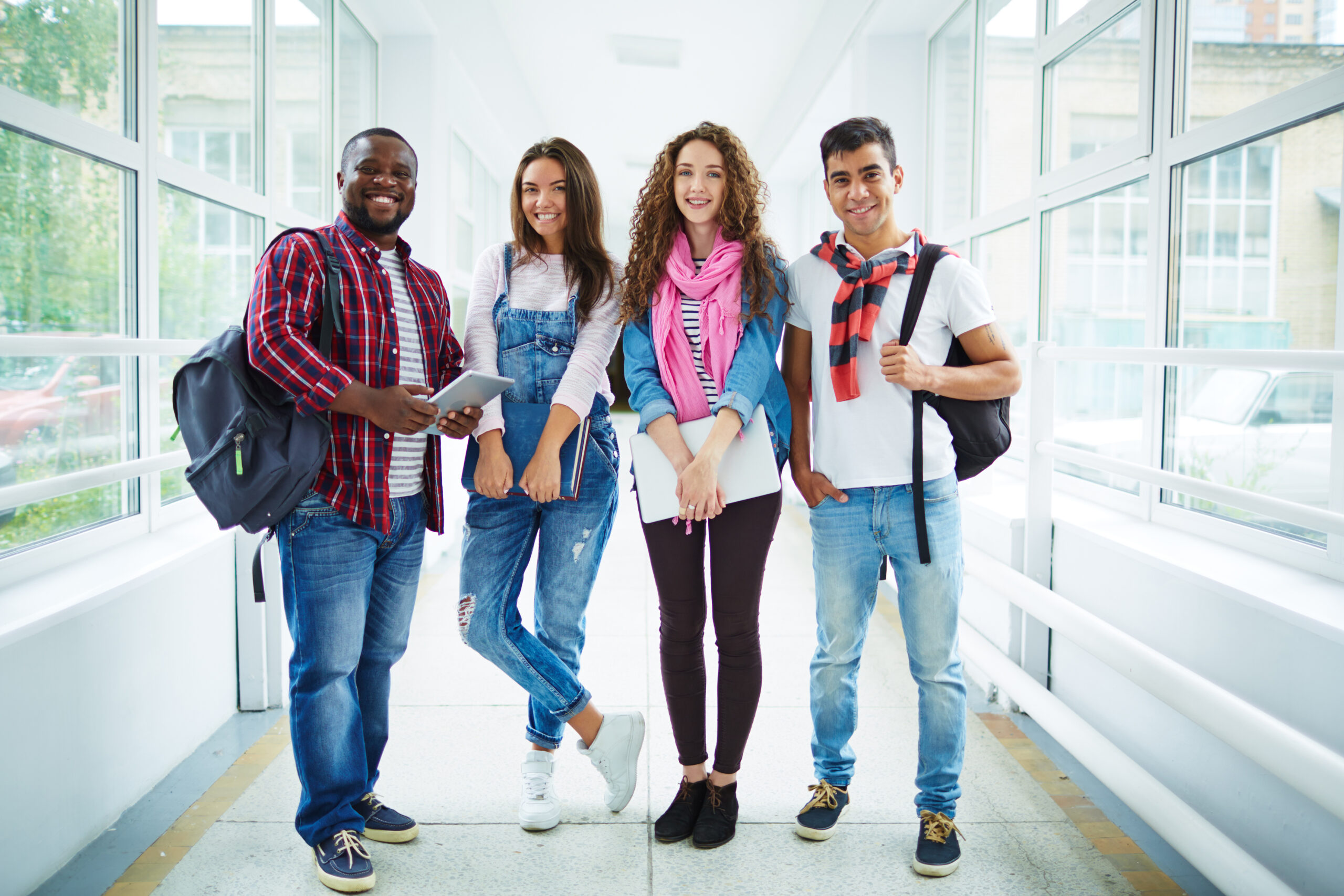 Friendly students in casual-wear standing in college corridor