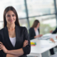 happy young business woman  with her staff,  people group in background at modern bright office indoors