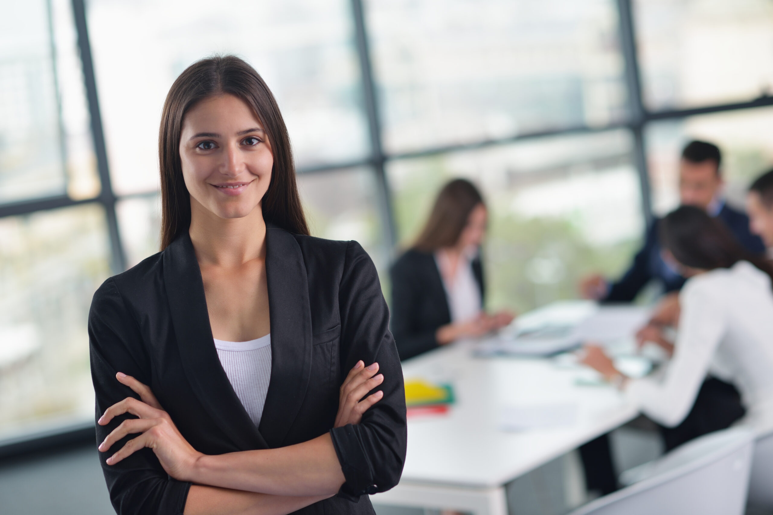 happy young business woman  with her staff,  people group in background at modern bright office indoors