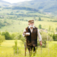 Old farmer with beard is walking in meadow