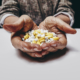 Old woman holding pills and medicine while sitting at a table. Focus on hands and pills. Close-up shot of senior female hands holding pills.