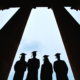 Outlines of four graduates between columns of university building