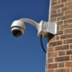 surveillance camera attached on a brick wall building (blue sky available)