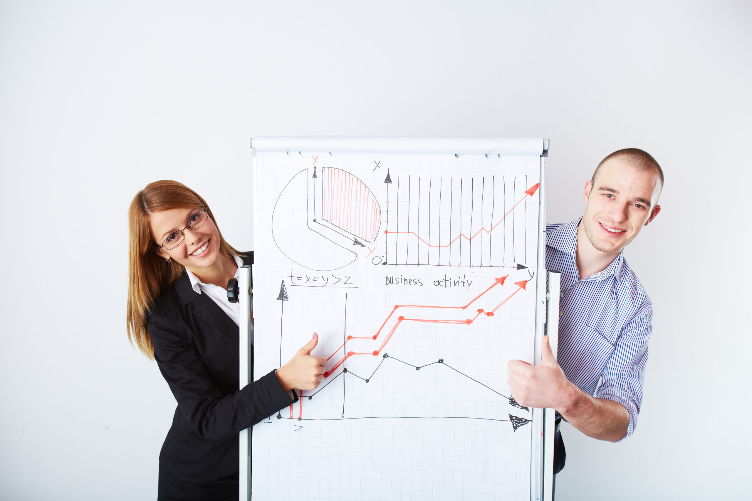 Successful business partners standing by whiteboard with graph of market analysis on it