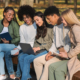 Multiracial students working on project in public park, looking at laptop screen together