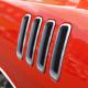 Close up detail of the louvered fender vents on a late model American muscle car with chrome accents.