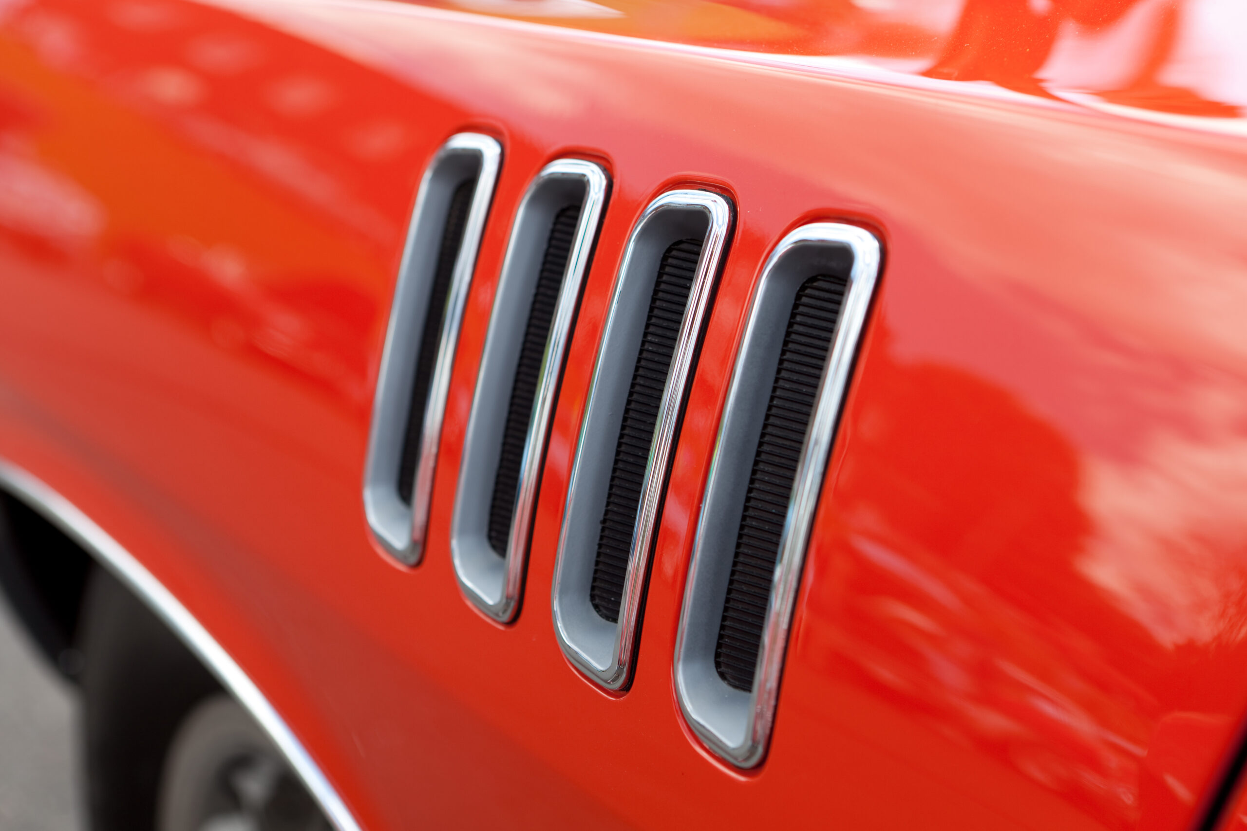 Close up detail of the louvered fender vents on a late model American muscle car with chrome accents.