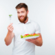 Portrait of a young handsome casual man eating salad isolated on white background