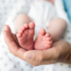 Unrecognizable father with newborn baby son, legs and hand. Close up.