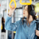 Young stylish woman enjoying trip in the public transport, standing with headphone while moving in the modern tram